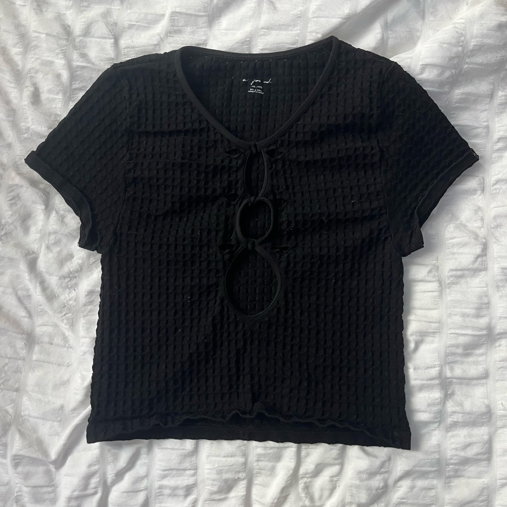black crop top with stretchy fabric and decorative holes.